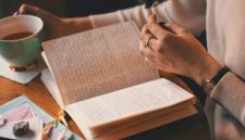 Seseorang sedang mencatat refleksi harian di atas buku jurnal dengan suasana hangat yang tenang, sebuah kebiasaan sederhana untuk mengurai beban pikiran dan menjaga kesehatan mental.