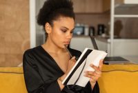 Seorang wanita menikmati momen tenang sambil menuliskan pikiran dan perasaannya di buku harian untuk meredakan stres serta merawat kesehatan mentalnya.