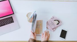 Seorang pekerja mengatur jadwal harian menggunakan agenda fisik dan komputer di meja kerja untuk menjaga produktivitas serta keseimbangan waktu pribadi.