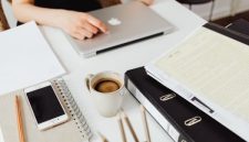 Seseorang sedang mengatur jadwal harian menggunakan buku catatan dan laptop di meja kerja yang tertata rapi untuk menciptakan alur kerja yang efisien.