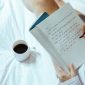 Seorang wanita menikmati momen tenang sembari menulis catatan harian di atas buku agenda kayu dengan secangkir kopi hangat di sampingnya. Kebiasaan menulis ini membantu menenangkan pikiran dan meredakan stres harian secara efektif.