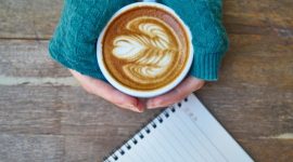 Seorang wanita meluangkan waktu sejenak di pagi hari untuk menuliskan gagasannya ke dalam buku harian. Kebiasaan merajut emosi lewat tulisan tangan dapat membantu memproses kecemasan serta memulihkan fokus mental.